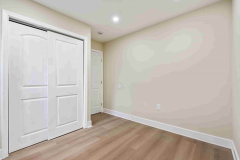 A room with a white door and wooden flooring.