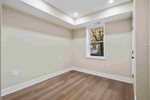 A room with a window and a picture frame on the wall.