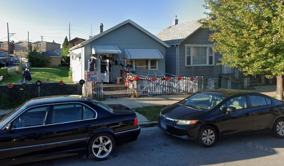 Two black cars parked in front of a house.