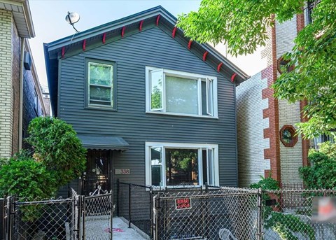 A grey house with a black fence in front.
