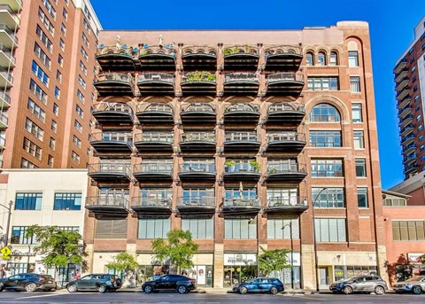 A large red brick building with balconies and a green plant on the balconies.
