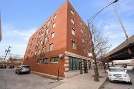 A red brick building with a parking lot in front.