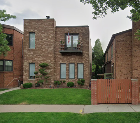 A brick house with a flag on the balcony.