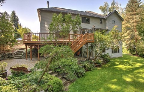 A house with a deck and a tree in front.