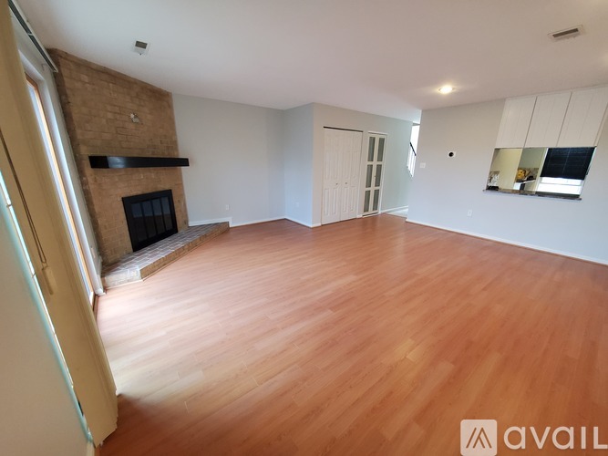 A spacious room with wooden flooring and a brick fireplace.