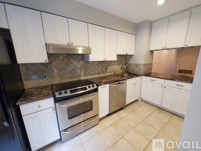 A kitchen with white cabinets and a black refrigerator.