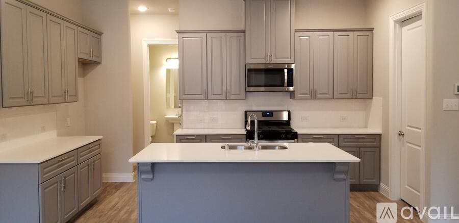 A kitchen with a white counter top and grey cabinets.