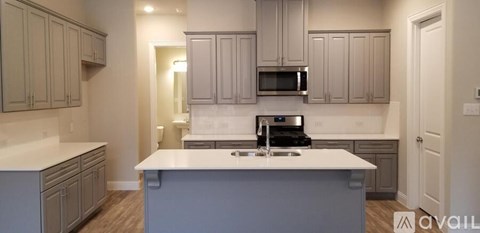 A kitchen with a white counter top and grey cabinets.