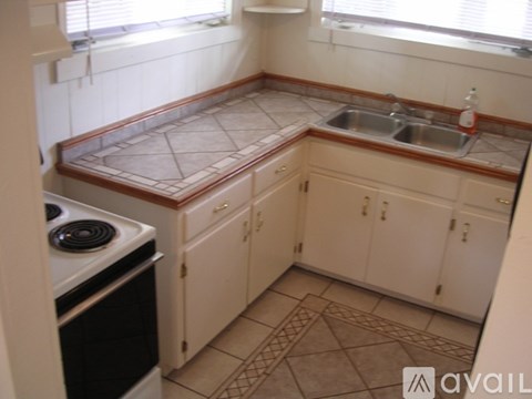 A kitchen with a stove, sink, and cabinets.