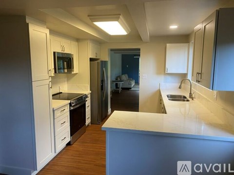 A kitchen with white cabinets and a wooden floor.