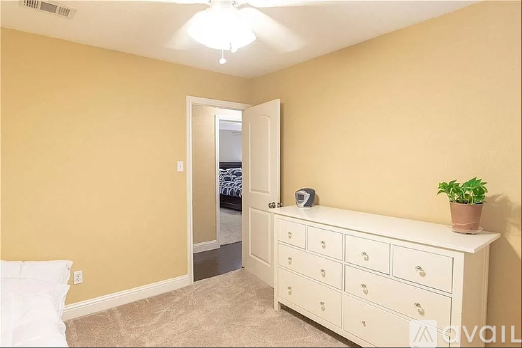A bedroom with a white dresser and a mirror.