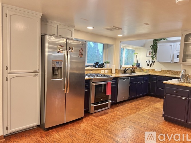 A kitchen with a refrigerator, oven, and sink.