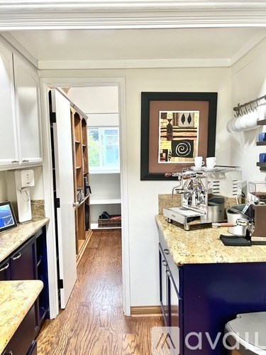 A kitchen with a marble counter top and a painting hanging above it.