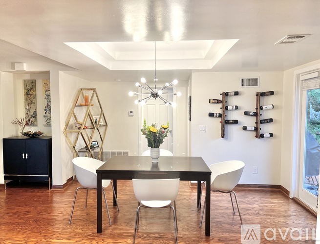 A modern dining room with a black table and white chairs.