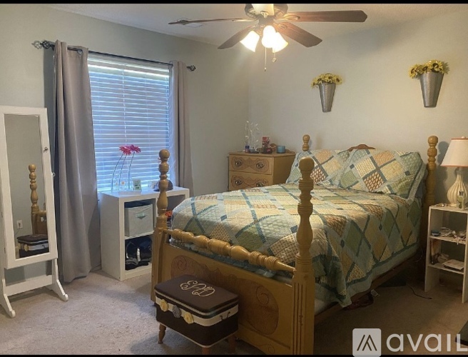 A bedroom with a bed, nightstand, and window with curtains.