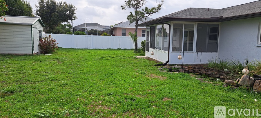 A backyard with a white fence and a small house.