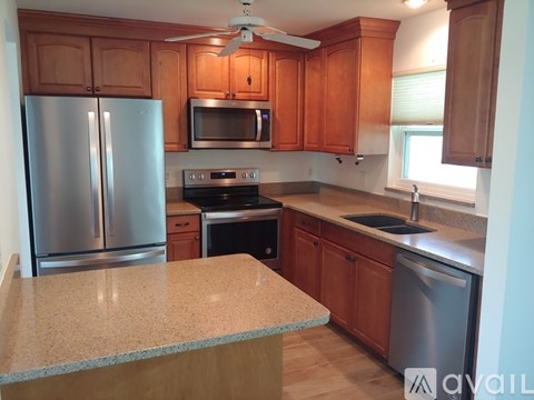 A kitchen with wooden cabinets and a stainless steel refrigerator.