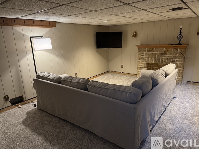 A living room with a grey couch and a flat screen TV mounted on the wall.