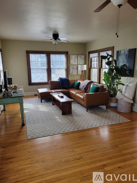 A living room with a brown couch and a ceiling fan.