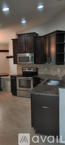 A kitchen with black cabinets and a granite countertop.