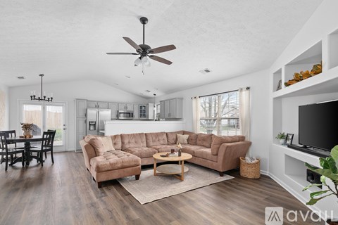 A living room with a brown sofa and a ceiling fan.