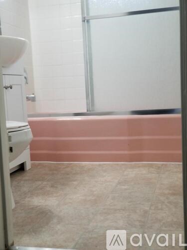 A white toilet sits in a bathroom with a pink wall.