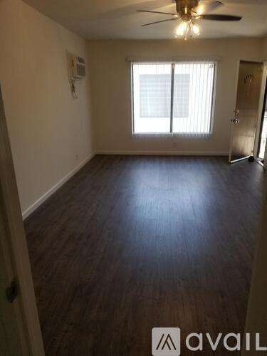 A room with a ceiling fan and wooden flooring.
