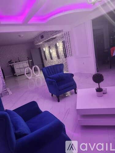A living room with a blue chair and a small table with a plant on it.