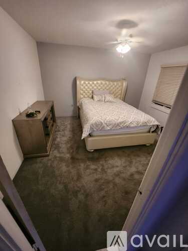 A bedroom with a bed, nightstand, and a ceiling fan.