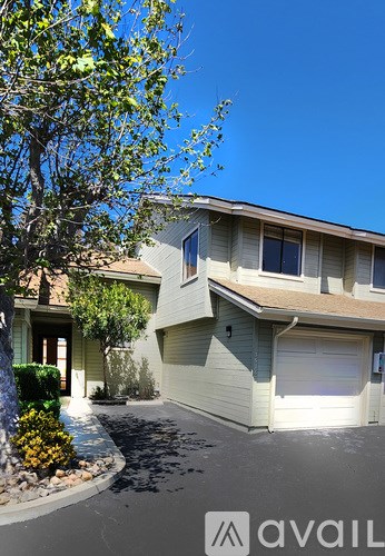 A house with a garage and a tree in front.