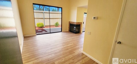 A room with wooden floors and a large window overlooking a garden.