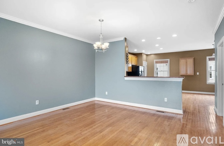A spacious room with wooden floors and a chandelier hanging from the ceiling.
