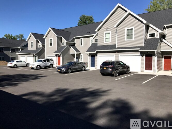 A row of houses with cars parked in front.