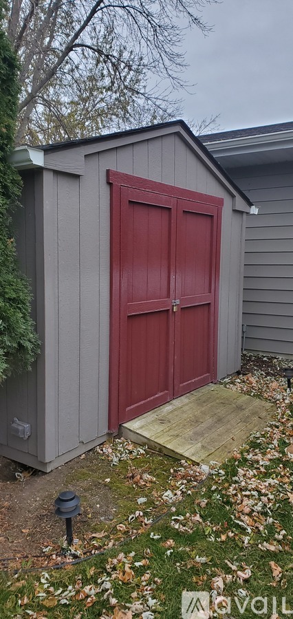 A red door is on a grey building.