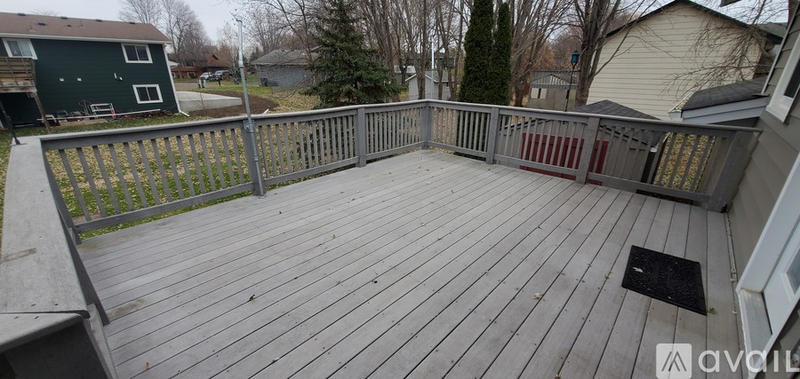 A wooden deck with a railing and a black mat on the floor.