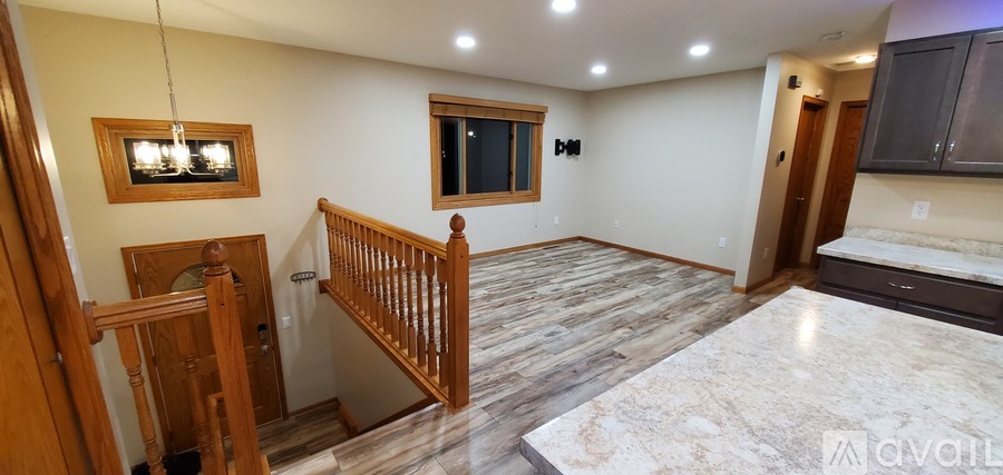 A spacious room with wooden flooring and a staircase.