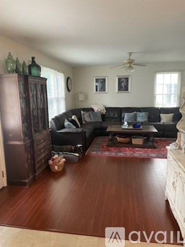 A living room with a black couch and a wooden floor.