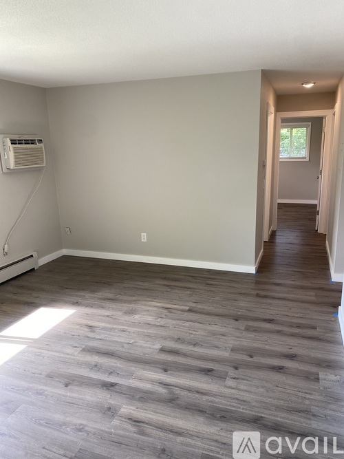 A spacious room with carpeted floor and a window on the right side.