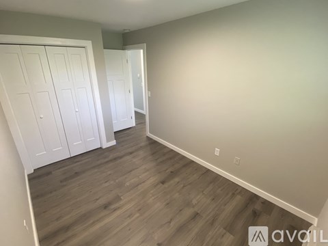 A room with wooden flooring and white closet doors.