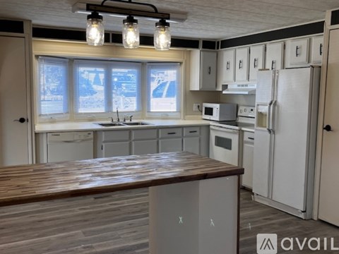 A kitchen with white appliances and wooden countertops.
