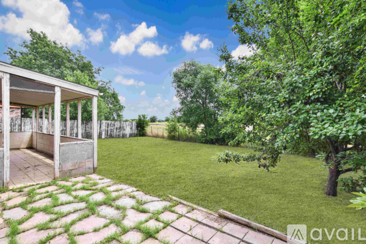 A patio area with a brick walkway and a white pergola.