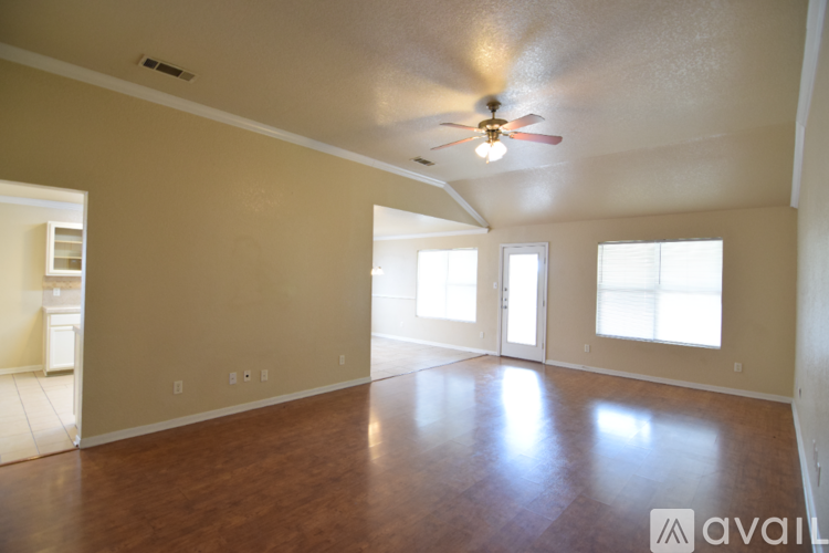 A spacious room with a ceiling fan and large windows.