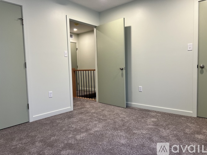 A room with carpeted floor and three doors.