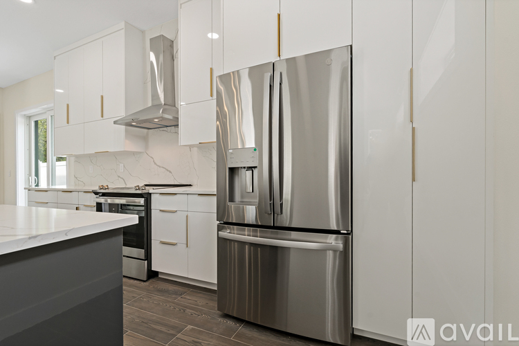 A modern kitchen with a stainless steel refrigerator and white cabinets.