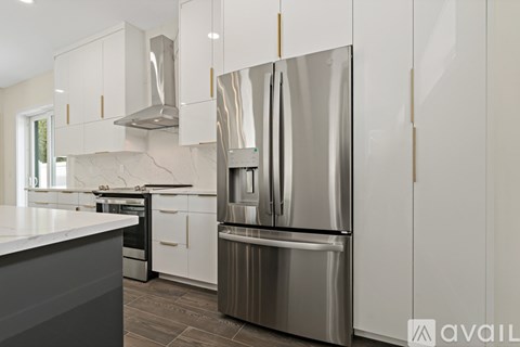 A modern kitchen with a stainless steel refrigerator and white cabinets.