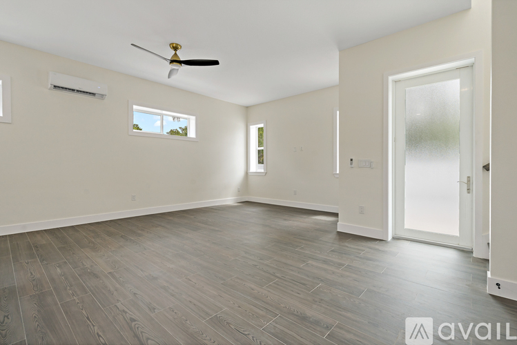 A spacious room with a ceiling fan and a door leading to another room.