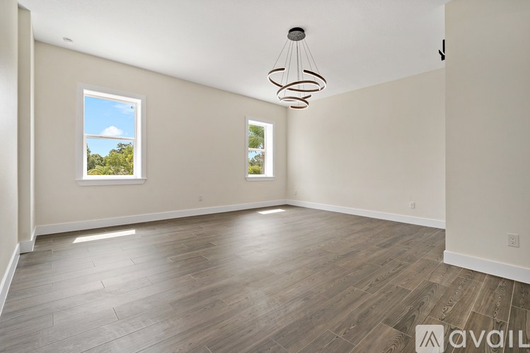 A room with wooden flooring and a window showing a view of trees.
