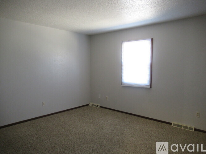 A room with a window and carpeted floor.