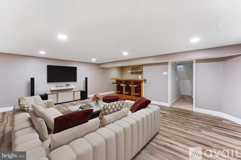A living room with a large couch and a television on the wall.
