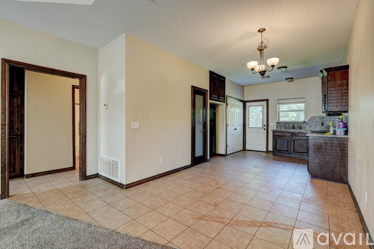 A living room with a tiled floor and a chandelier hanging from the ceiling.
